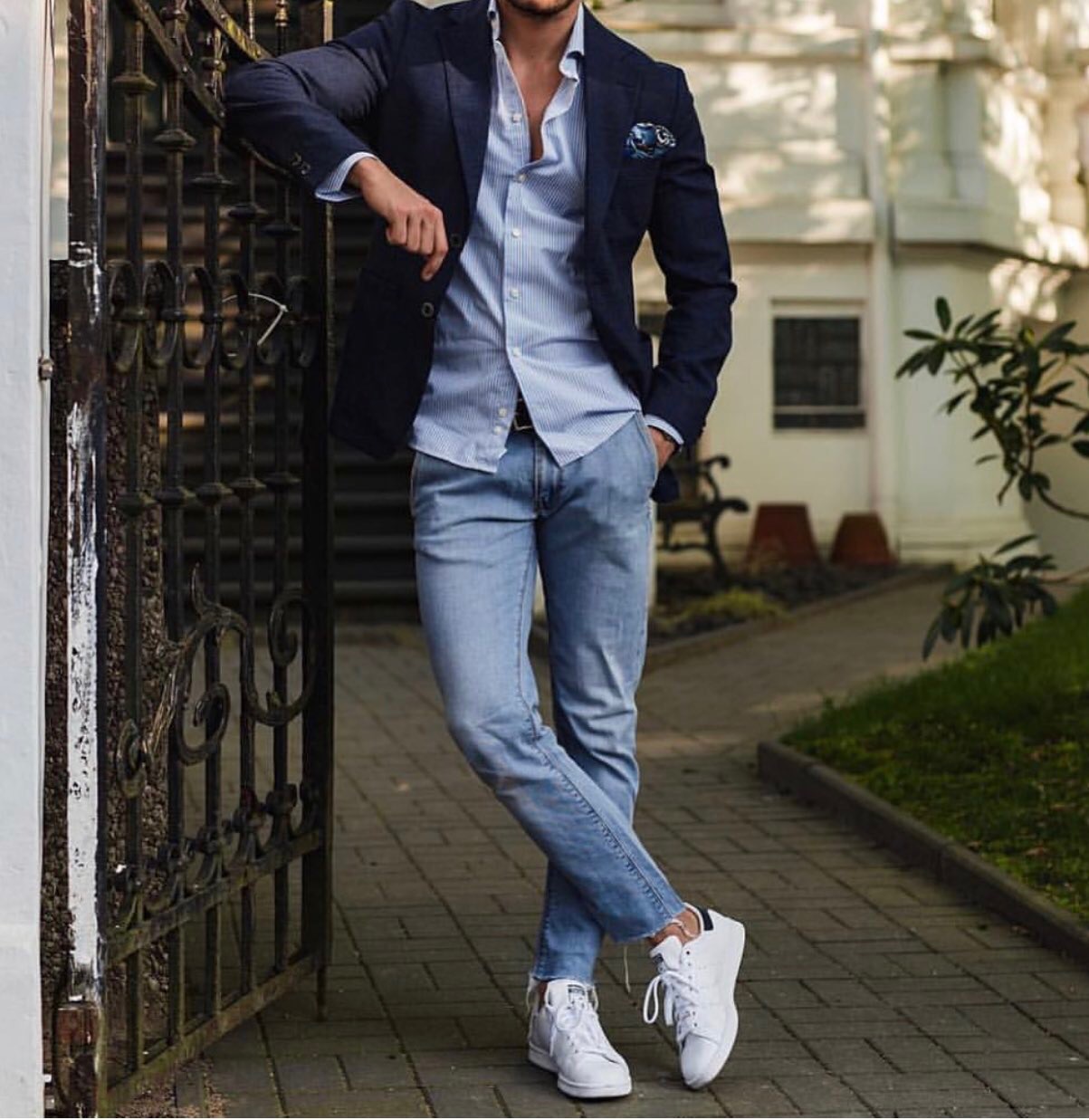 Man in stylish navy blue coat partnered with a light blue button-down shirt, jeans and sneakers